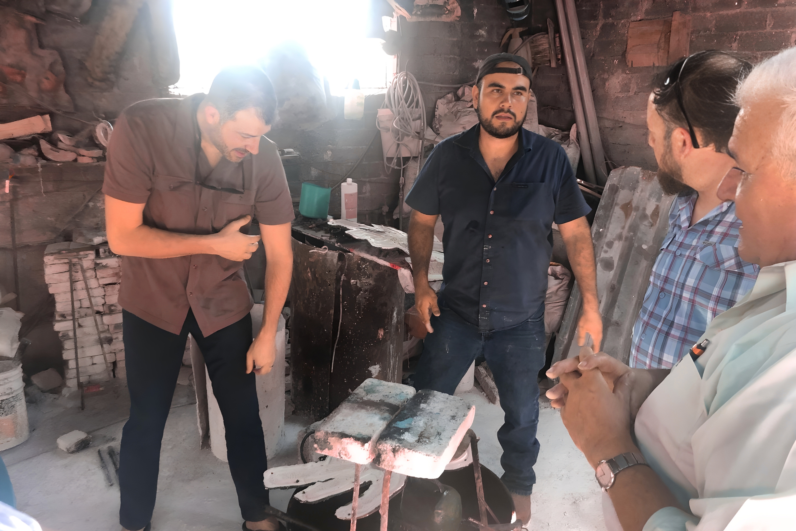 Men discussing craftsmanship in a workshop, with tools and materials visible, reflecting the mission of discipleship and community engagement in Cuautla, Mexico.