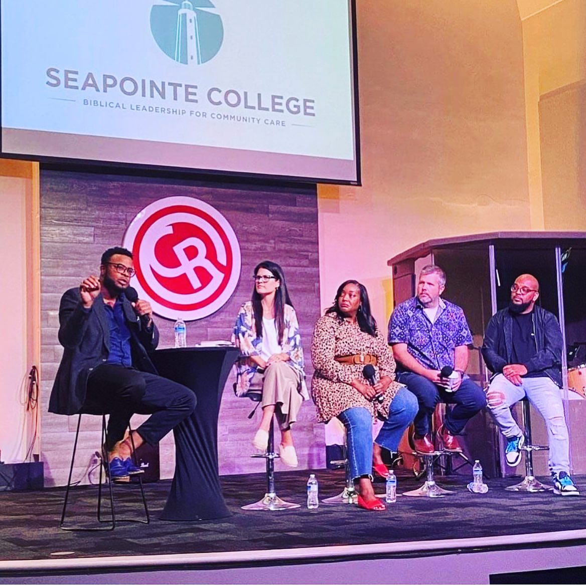 Panel discussion featuring diverse speakers at Seapointe College event, highlighting biblical leadership for community care, with the college logo displayed prominently.
