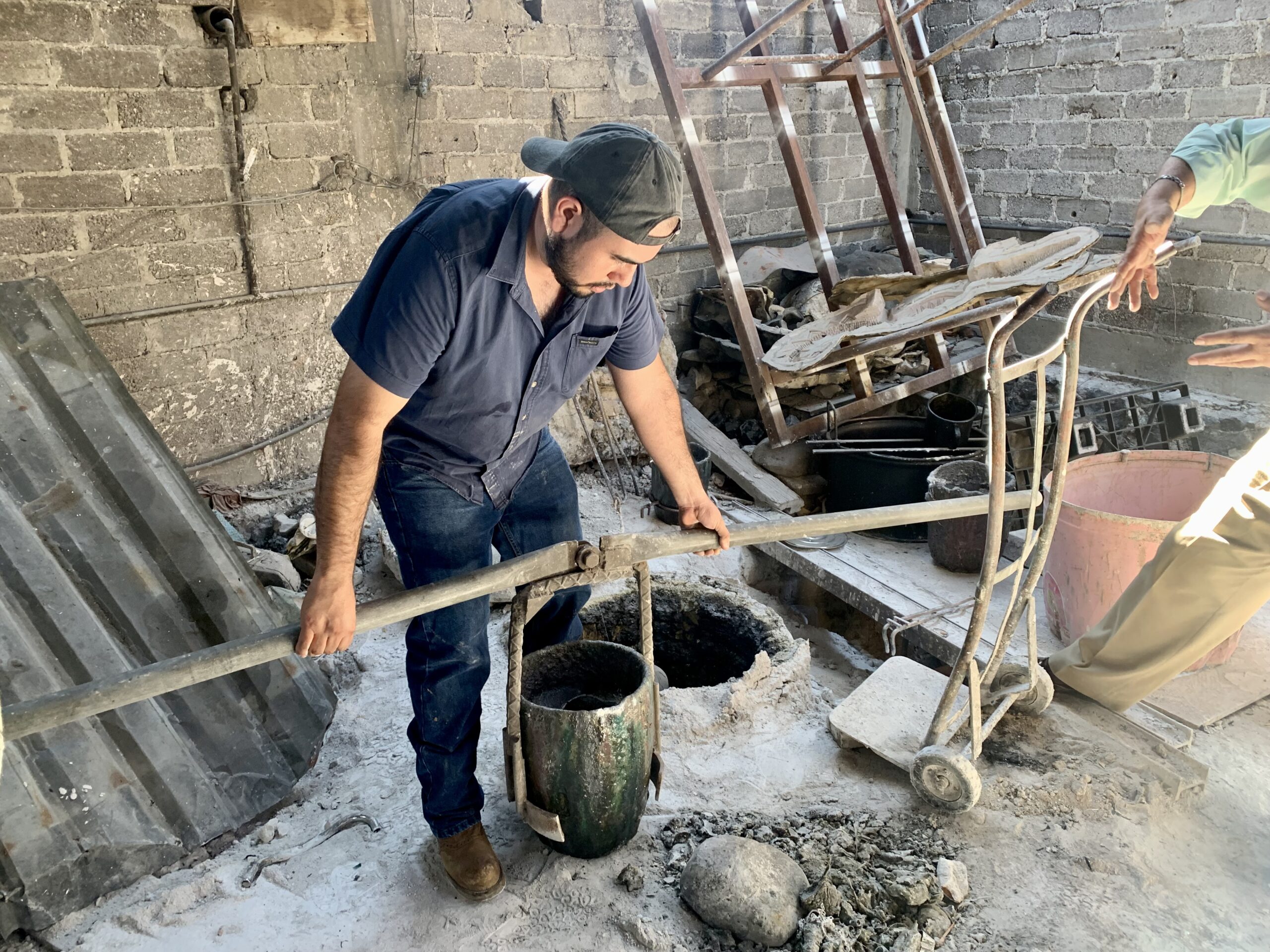 Man operating a manual concrete mixer in a construction site, surrounded by tools and materials, illustrating hands-on leadership and community engagement in Cuautla, Mexico.