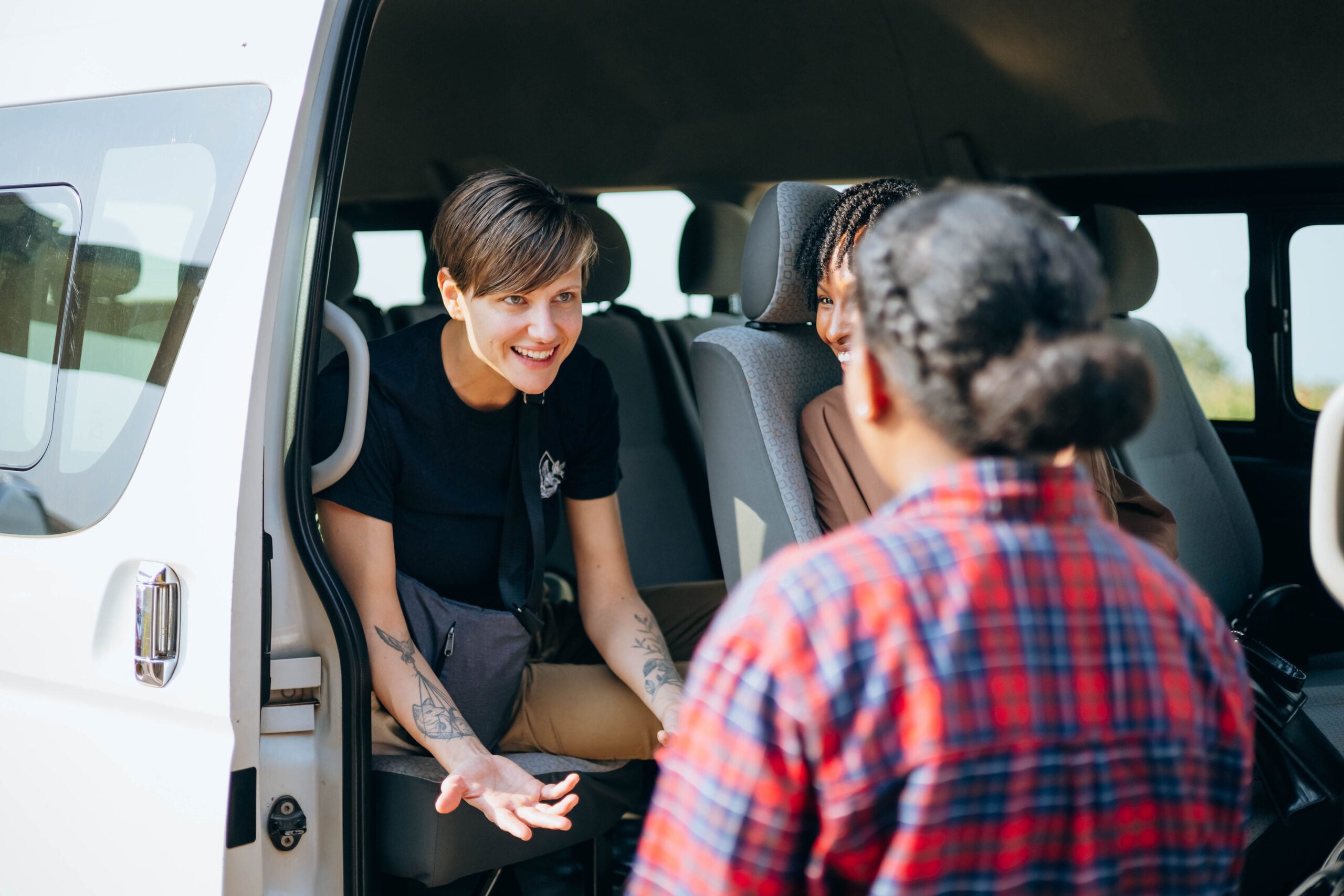 Woman engaging with two individuals near a van, highlighting community connection and support for discipleship initiatives.
