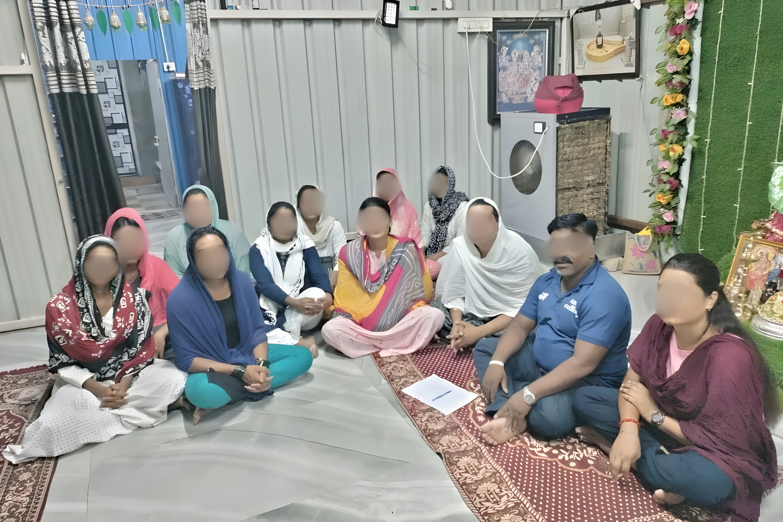 Group of individuals seated in a circle, engaged in a community gathering, surrounded by cultural decor, emphasizing support and empowerment for marginalized communities in India.