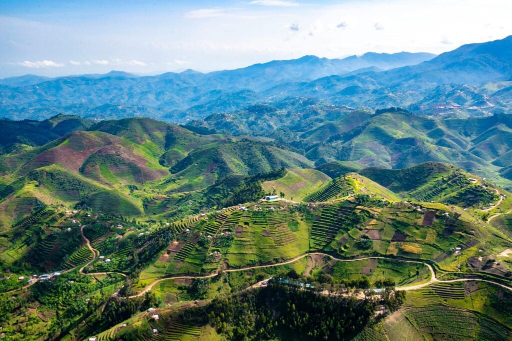 Aerial view of lush green hills and valleys in Rwanda, representing the landscape where the Rusasa Pathway project supports community growth and decentralized church gatherings.