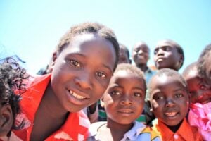 Group of children smiling and looking at the camera, representing community engagement and hope in Rwanda, aligned with the Rusasa Pathway project’s mission to support Pastor Jean and his congregation.