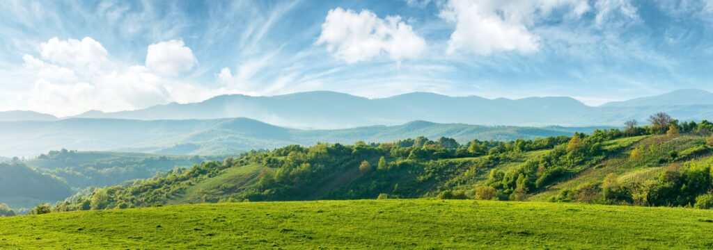 Rolling hills and open fields under soft sky