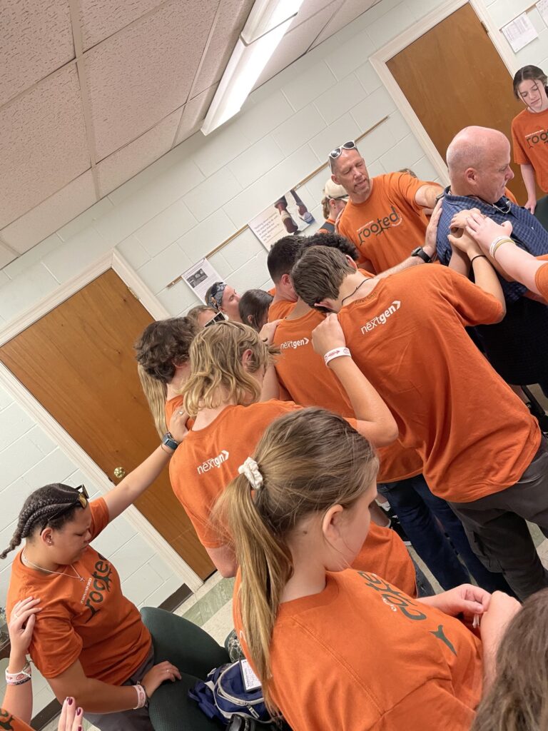 Group of young people gathered indoors wearing orange shirts