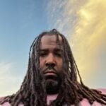 Portrait of man with long hair against sky background