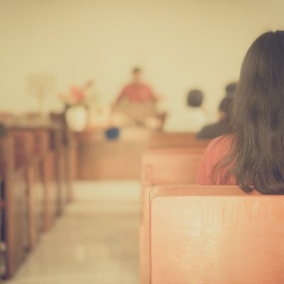 Person seated in church pew facing altar