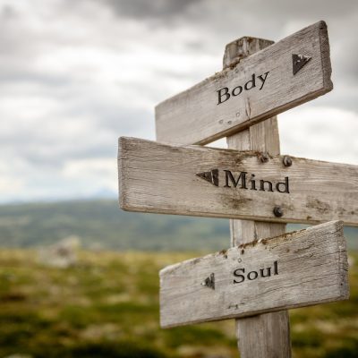 Wooden signpost with directional arrows labeled "Body," "Mind," and "Soul," symbolizing holistic well-being and self-leadership in a natural setting, relevant to church leadership and disciple-making resources.