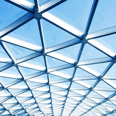 Geometric glass ceiling structure with blue sky background, symbolizing openness and connection in church leadership discussions.