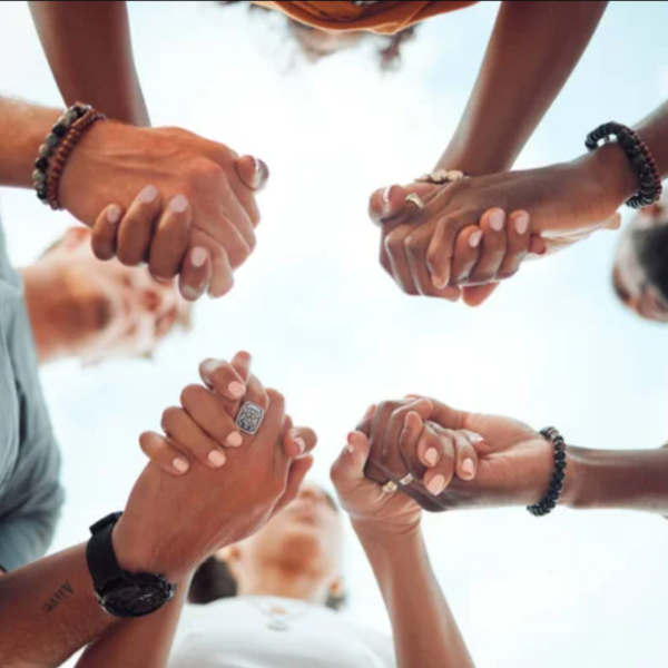 People holding hands in a circle outdoors