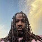 Portrait of man with long hair against neutral background