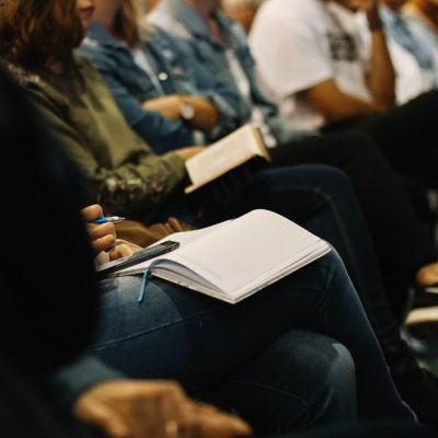 Audience members engaged in discussion during a church planting podcast episode, with a focus on note-taking and community involvement.