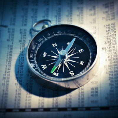 Compass resting on financial documents symbolizing direction in business and mission work.